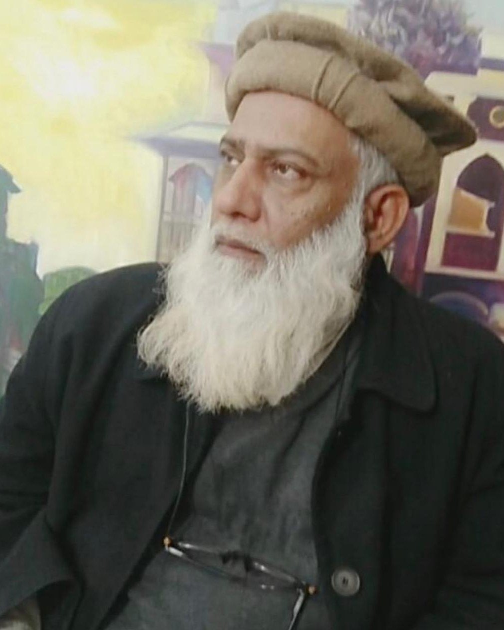Saifullah Nafeesi photographed in his studio, his paintings behind him